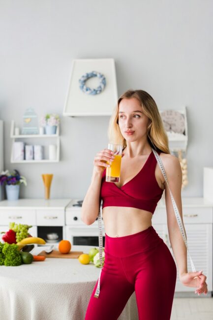 sporty-woman-in-kitchen-with-healthy-juice_23-2148193170